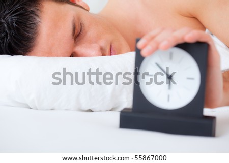 Sleeping man  putting on snooze button while alarm is ringing