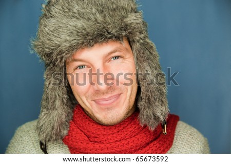 Happy funny male portrait looking snowflakes falling down wearing hat and scarf in december season