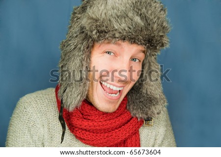 Happy funny male portrait looking snowflakes falling down wearing hat and scarf in december season