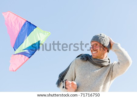 Smiling happy healthy man walking on beach with kite in winter autumn spring time