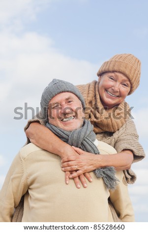 senior couple with blue sky in background having fun in autumn season on the coast in vacation
