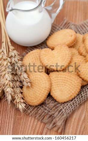 biscuits on wooden surface and pitcher of milk