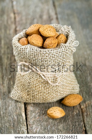 almonds in a  burlap bag on wooden surface