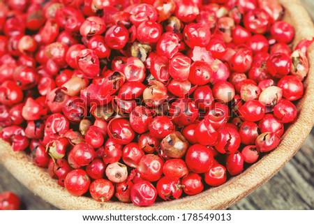 pink peppercorn in a spoon on wooden background