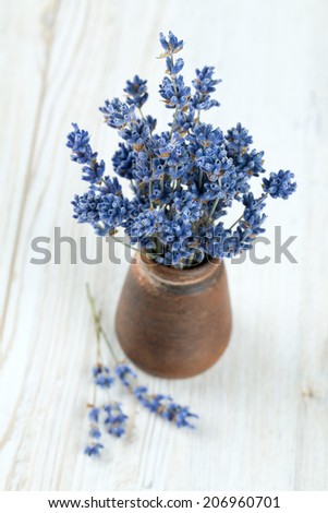 dried lavender in a miniature clay vase on wooden surface