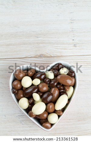 chocolate covered nuts and raisins in a heart-shaped bowl