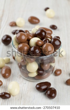 chocolate covered nuts and raisins on wooden surface