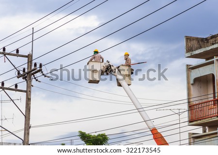 electricians in buckets boosted by a boom crane to repair power lines, very dangerous job