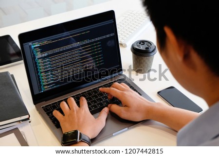 A male programer working with laptop and coding on computer.