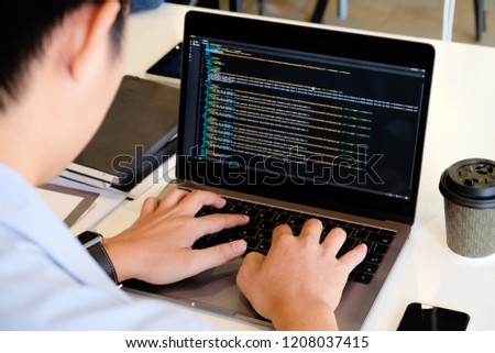 A male programer working with laptop and coding on computer.