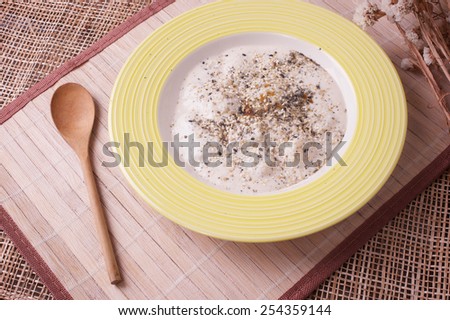 Oat milk porridge in a yellow bowl and wood spoon