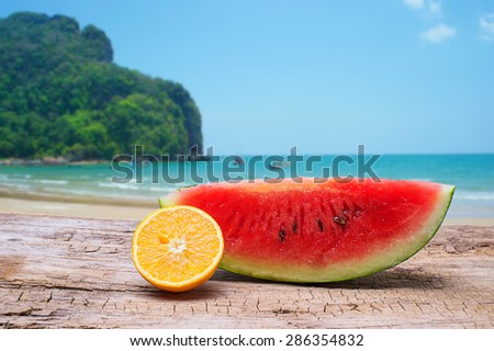 Watermelon slice and Orange slice on wooden and beach background with clipping part