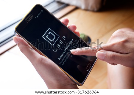 CHIANG MAI,THAILAND - SEP 16,2015 : A woman hand holding Uber app showing on Samsung note 3,Uber is smartphone app-based transportation network.