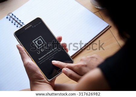 CHIANG MAI,THAILAND - SEP 16,2015 : A woman hand holding Uber app showing on Samsung note3 ,Uber is smartphone app-based transportation network.