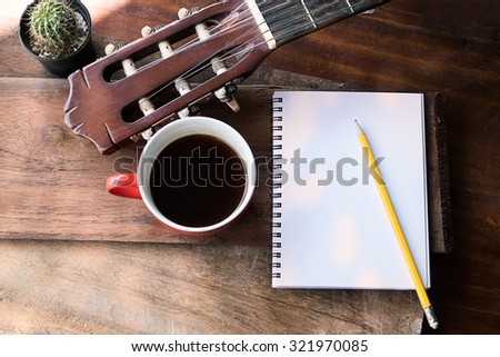 Inspirational background with classical guitar on a wooden table.Score sheet, a pencil and a cup of coffee for the music composer,vintage effect.
