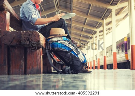 A man sit with map. travel bag at the train station.