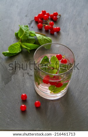 Cold drink with red arrow wood berries and mint on dark stone background