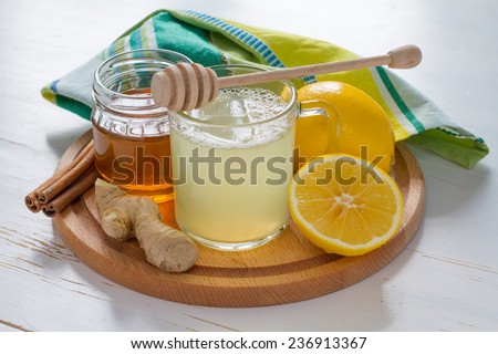 Cold care - tea, honey, lemon, ginger, cinnamon sticks on white wood background