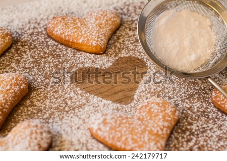 Heark shaped cookies with strainer with sugar powder on wood background