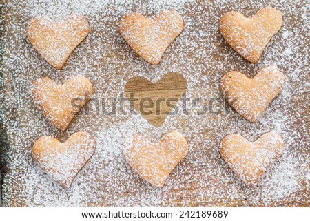 Heart shaped cookies with sugar powder on wood background, top view