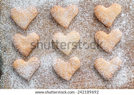 Heart shaped cookies with sugar powder on wood background, top view