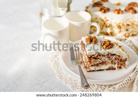 Carrot cake slice on white plate with coffee maker and cups on light background