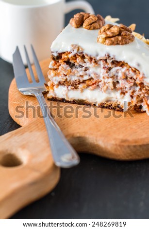 Carrot cake slice on wood board with coffee maker on dark stone background