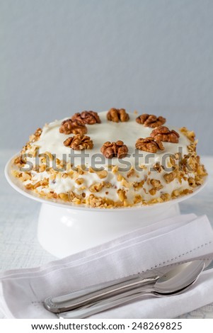 Carrot cake with walnuts and white frosting on cake stand