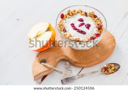 Smile face - apple granola with yogurt and jam in glass bowl on apple shaped wood board, white wood background