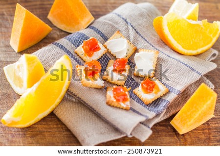 Jam ingredients - orange, lemon, pumpkin and crisp bread on dark wood background