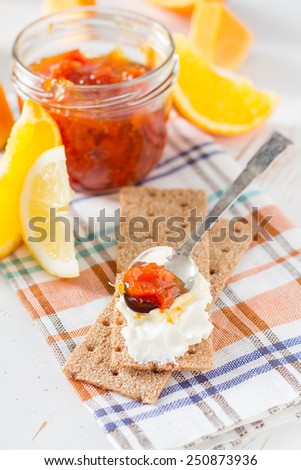 Jam ingredients - orange, lemon and crisp bread on white wood background