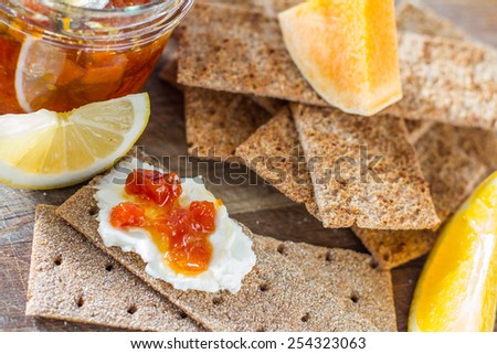 Pumpkin jam in glass jar, orange, lemon, pumpkin slices, crisp bread, wood background