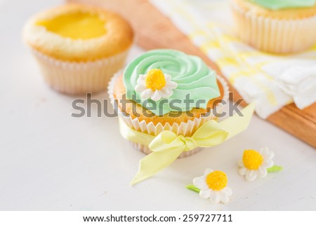 Spring cupcakes preparation - sugar flowers, ribbon, plaid napkin, white wood background