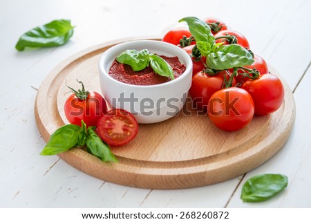 Tomato sauce and ingredients - cherry tomatoes, basil, wood board, white wood background