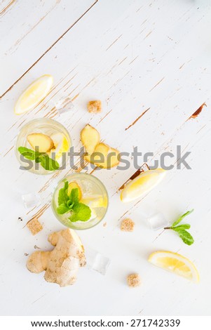 Ginger lemonade and ingredients - ginger, lemon, lime, mint, sugar, ice, white wood background, top view
