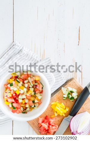 Gazpacho summer soup in white bowl and ingredients - tomato, pepper, onion, garlic, lime, olive oil, white wood background, top view