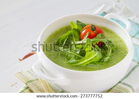 summer ruccola pure soup with cherry tomato and bread, white wood background