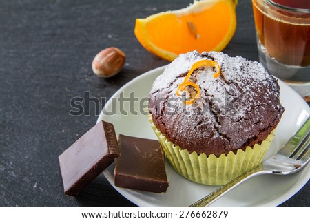 Chocolate and orange cupcakes, nuts, orange slice, chocolate, coffee maker, white plates, dark stone background