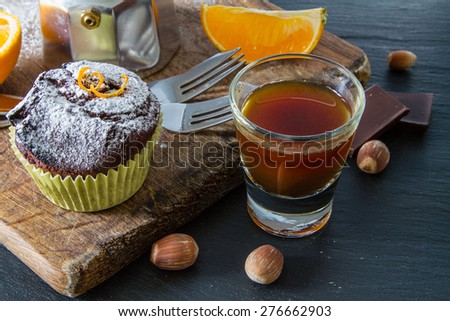 Chocolate and orange cupcakes, nuts, orange slice, chocolate, coffee maker, wood board, dark stone background