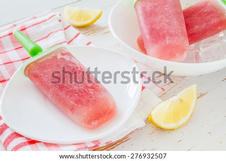 Watermelon fruit ice pops on white plate, knitted napkin, white wood background
