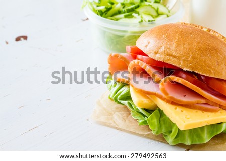 Lunch box - sandwich, milk, salad, white wood background