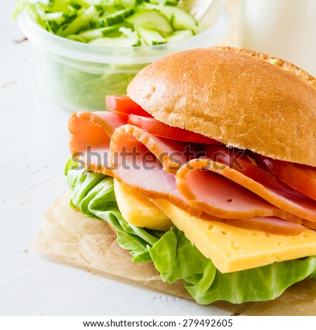 Lunch box - sandwich, milk, salad, white wood background, closeup