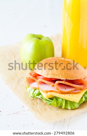 Lunch box for school - sandwich, juice, apple, white wood background, closeup