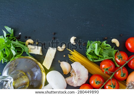 Italian cooking background - tomatoes, mushrooms, cheese, garlic, onion, pepper, pasta, dark stone background, top view