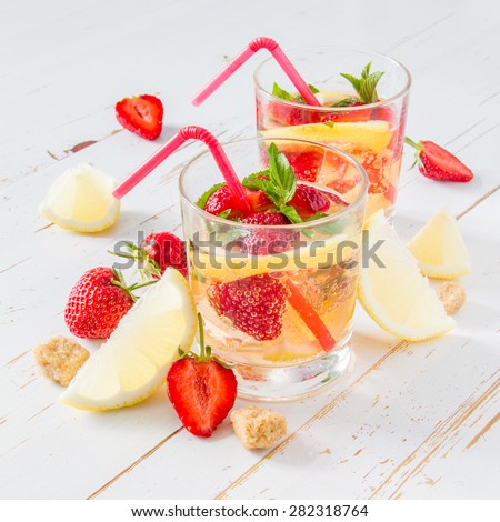 Strawberry lemonade and ingredients - strawberry, lemon, sugar, ice, white wood background