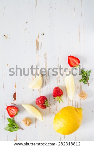 Strawberry lemonade and ingredients - strawberry, lemon, sugar, ice, white wood background, top view