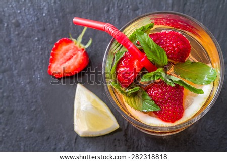 Strawberry lemonade and ingredients - strawberry, lemon, sugar, ice, dark stone background, closeup, top view