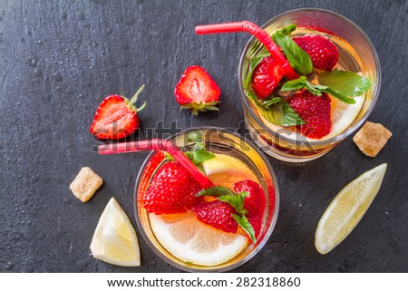 Strawberry lemonade and ingredients - strawberry, lemon, sugar, ice, dark stone background, closeup, top view