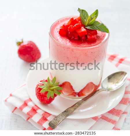 Strawberry frozen dessert in glass with mint, plaid napkin, light blue background