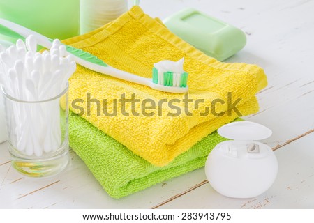 hygiene - towel, soap, lotion, cotton sticks and pads, tooth brush, floss, white wood background